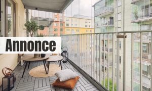 A large glass enclosed balcony with a small sofa, tables and various home decor.