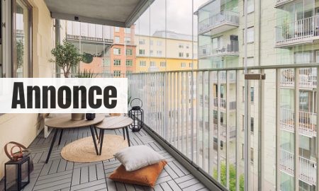 A large glass enclosed balcony with a small sofa, tables and various home decor.